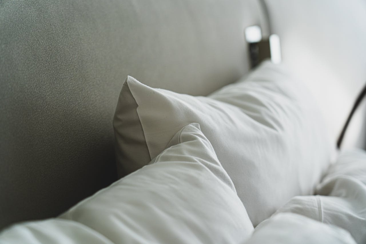 services-04 A close-up view of cozy white pillows and bedding in a modern bedroom.